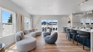 Cocina moderna con barra, ventanas amplias y zona de estar con sofá y sillones.