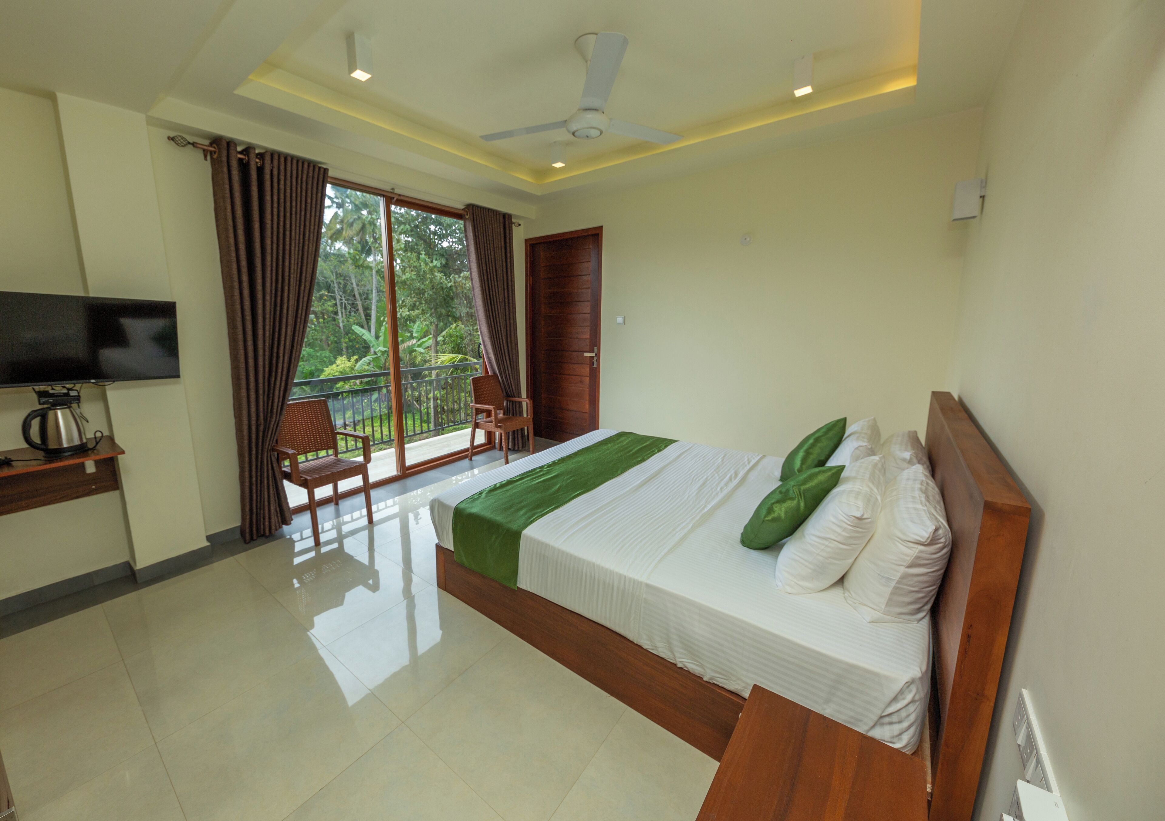 A hotel room with a bed, a TV, a balcony with a chair, and a door.