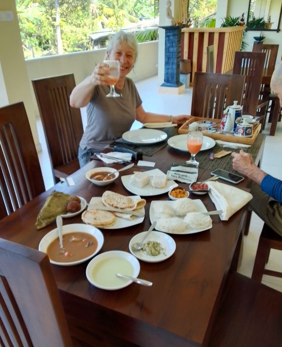 A dining table with various dishes, a glass of orange juice, and a bottle of water.