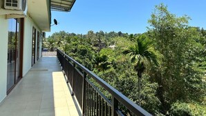Un balcon offrant une vue sur une végétation luxuriante et un ciel dégagé.