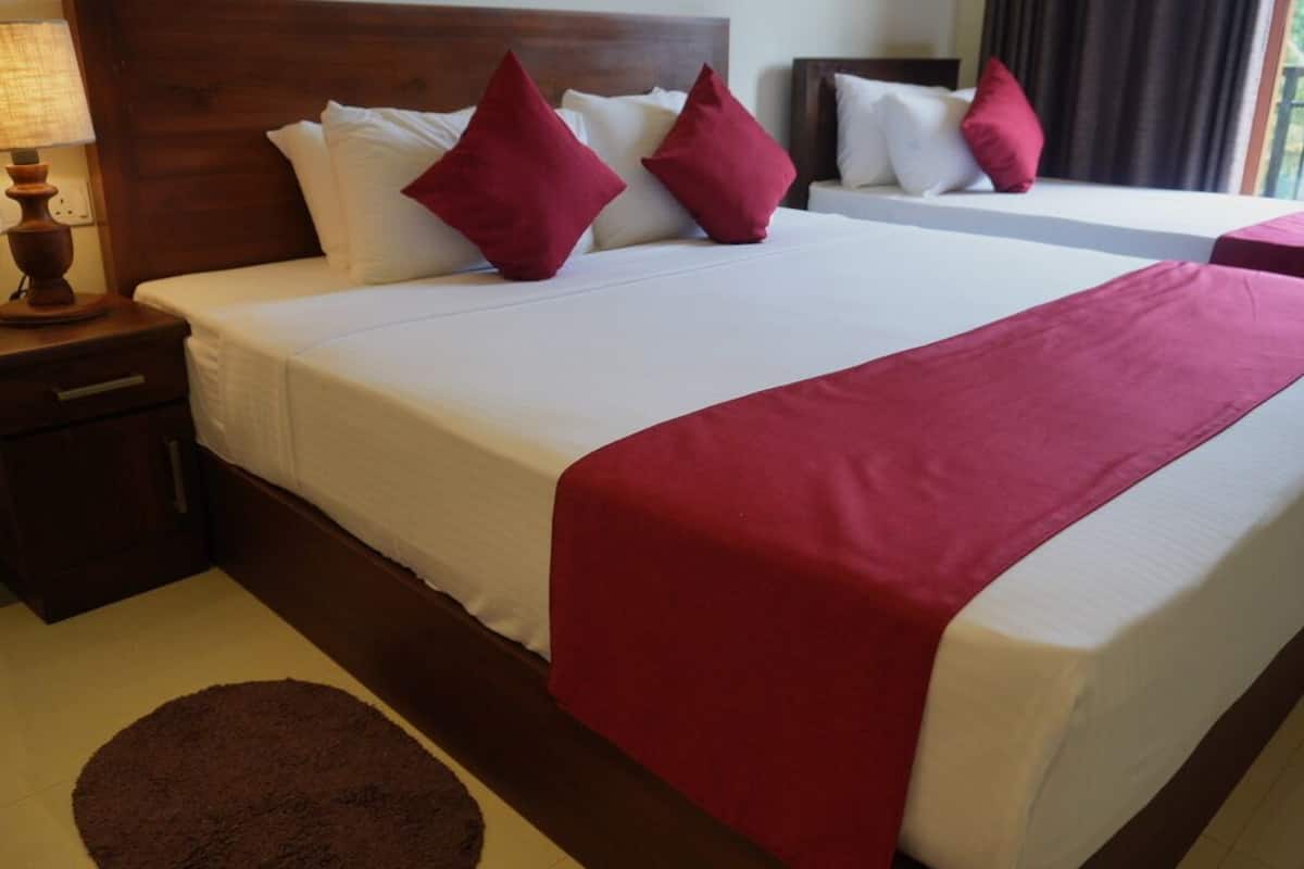 Habitación de hotel con una cama grande, dos almohadas, una mesita de noche, una lámpara y vistas al exterior.