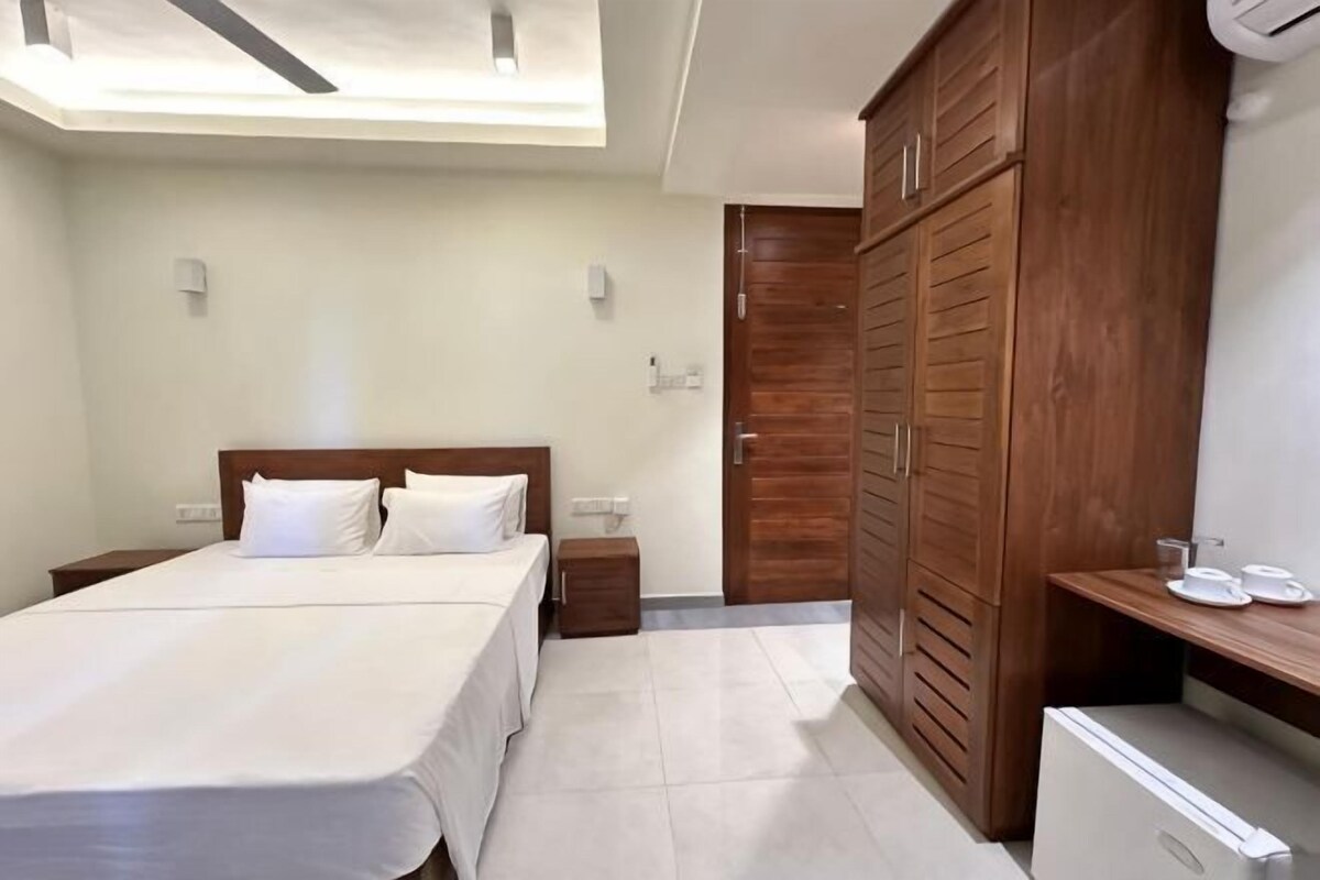 Un dormitorio con cama, mesitas de noche, armario y escritorio con silla.