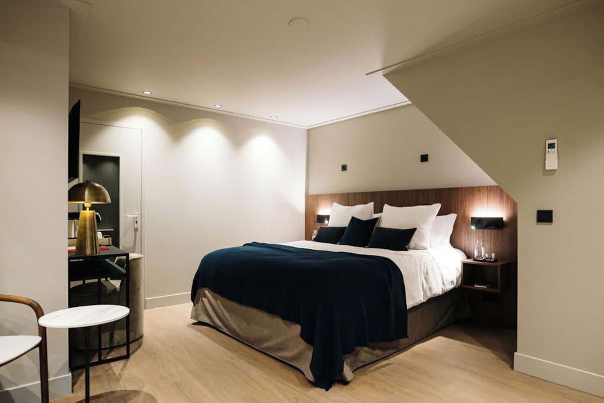 A modern bedroom with a large bed, a desk, and a chair.