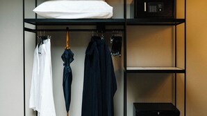 Un meuble de rangement moderne à plusieurs niveaux, avec un téléviseur à écran plat, une valise, ainsi que des vêtements et des chaussures rangés avec soin.