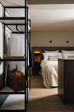 A hotel room with bunk beds, a bedside table with a lamp, a suitcase, and a wooden headboard.