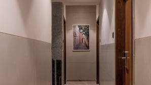 Un pasillo con suelo de mármol, paredes color crema y una puerta de madera a la derecha.