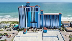 Un grand hôtel à plusieurs étages, avec vue sur la plage et un parking.