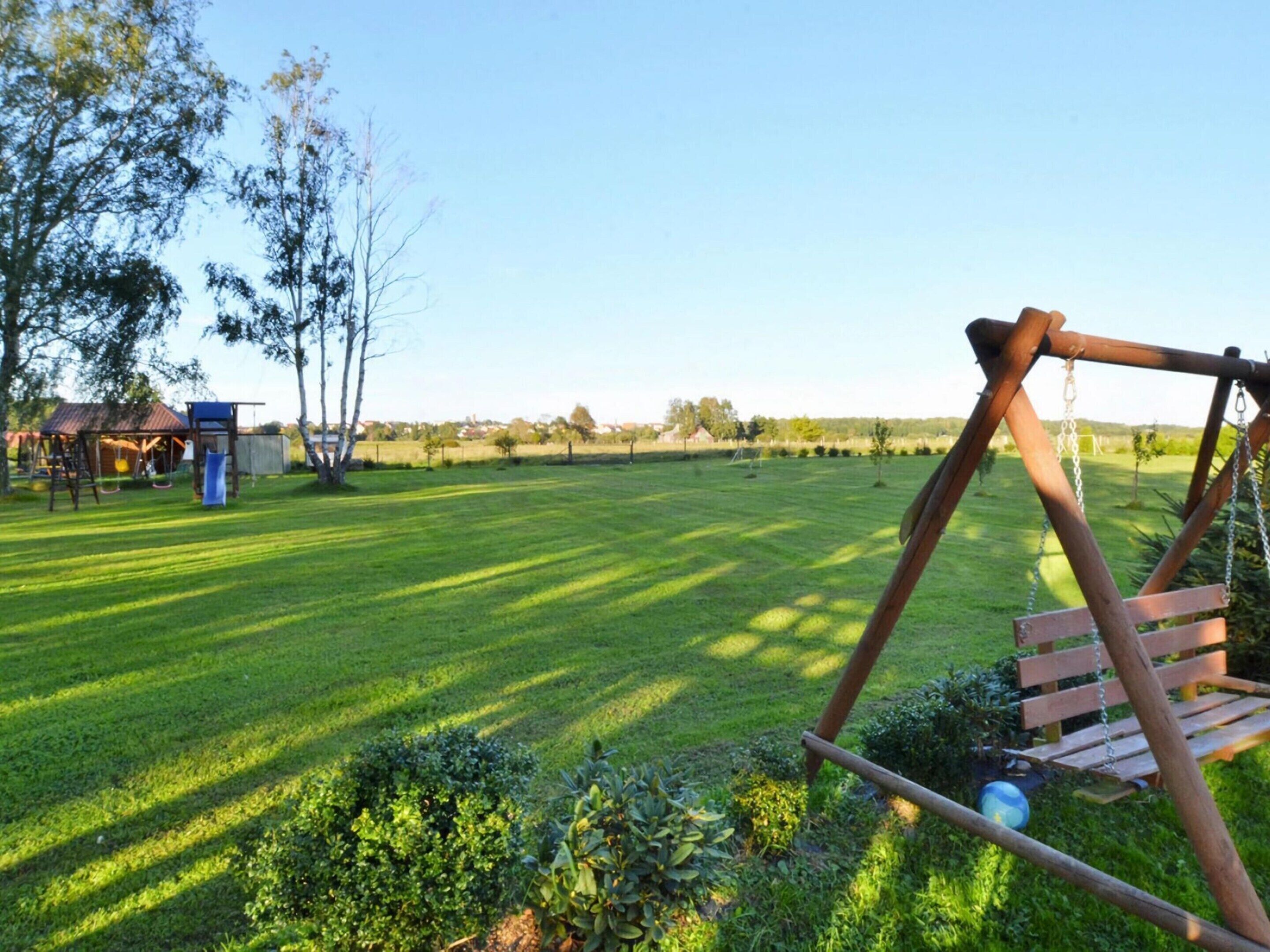 A grassy outdoor area with a swing set and a small shed.