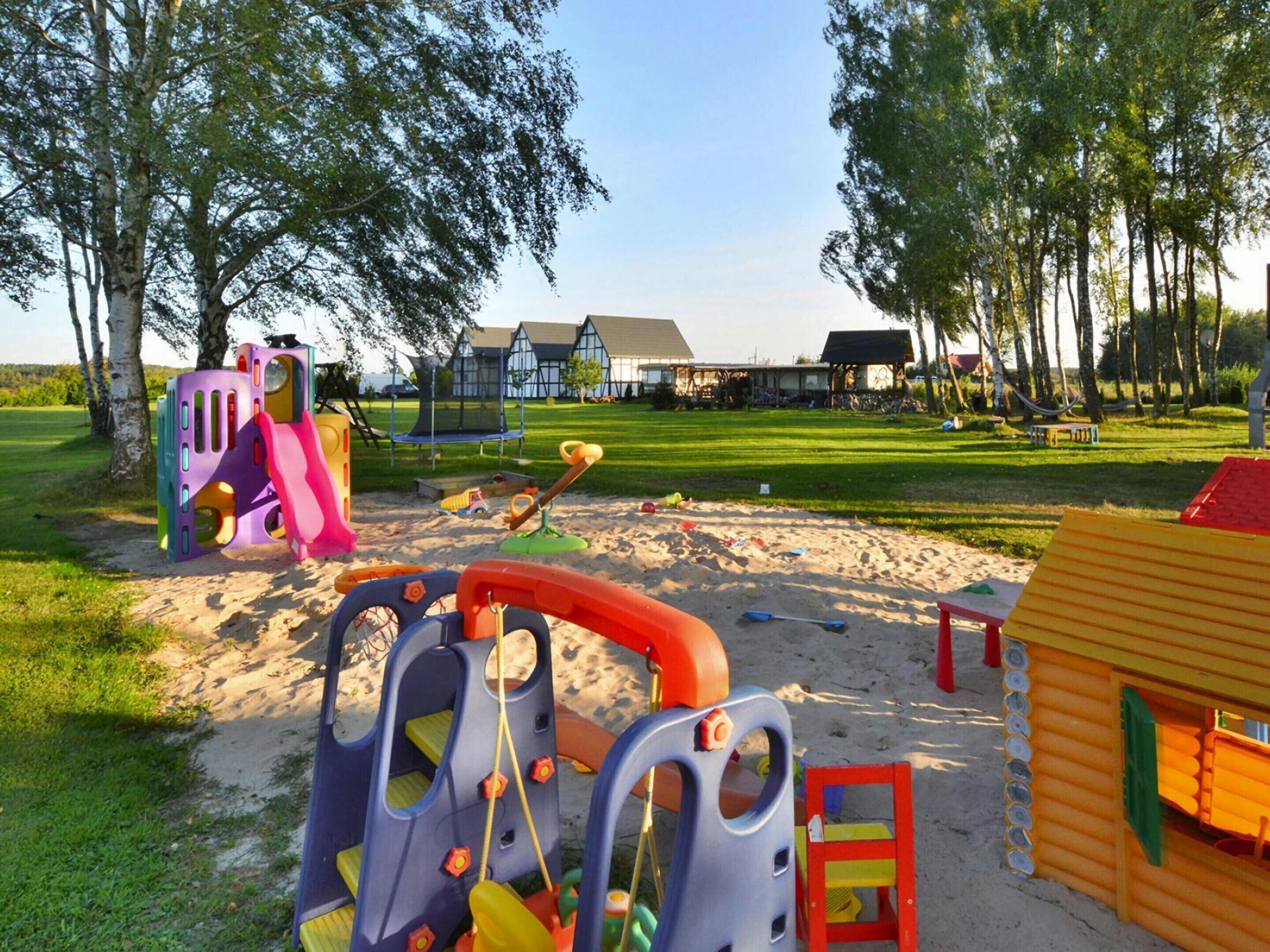 A playground with various play structures, a sand area, and a wooden playhouse.
