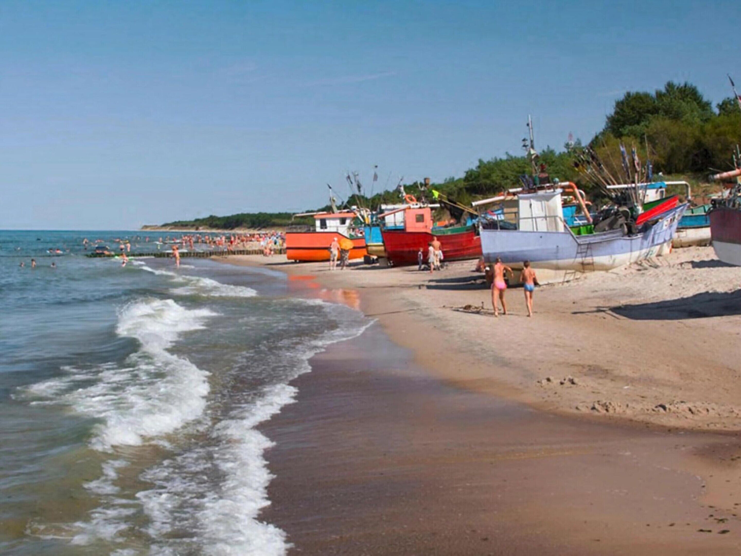A beach with boats and people.