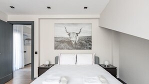 A modern bedroom with a large bed, two bedside tables, and a wall-mounted artwork of a bull.