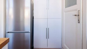 A kitchen with a stainless steel refrigerator, white cabinets, and a wooden countertop.