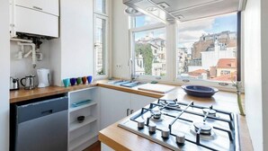 A modern kitchen with a gas stove, a sink, and a window overlooking a cityscape.