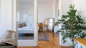 A bedroom with a bed, bedside tables, a mirror, and a plant.