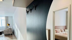 A modern hotel room with a curved wall, a bed with a wooden headboard, a floor lamp, and a sofa. - Joy City Stay Nord One N2-1 (Timișoara)