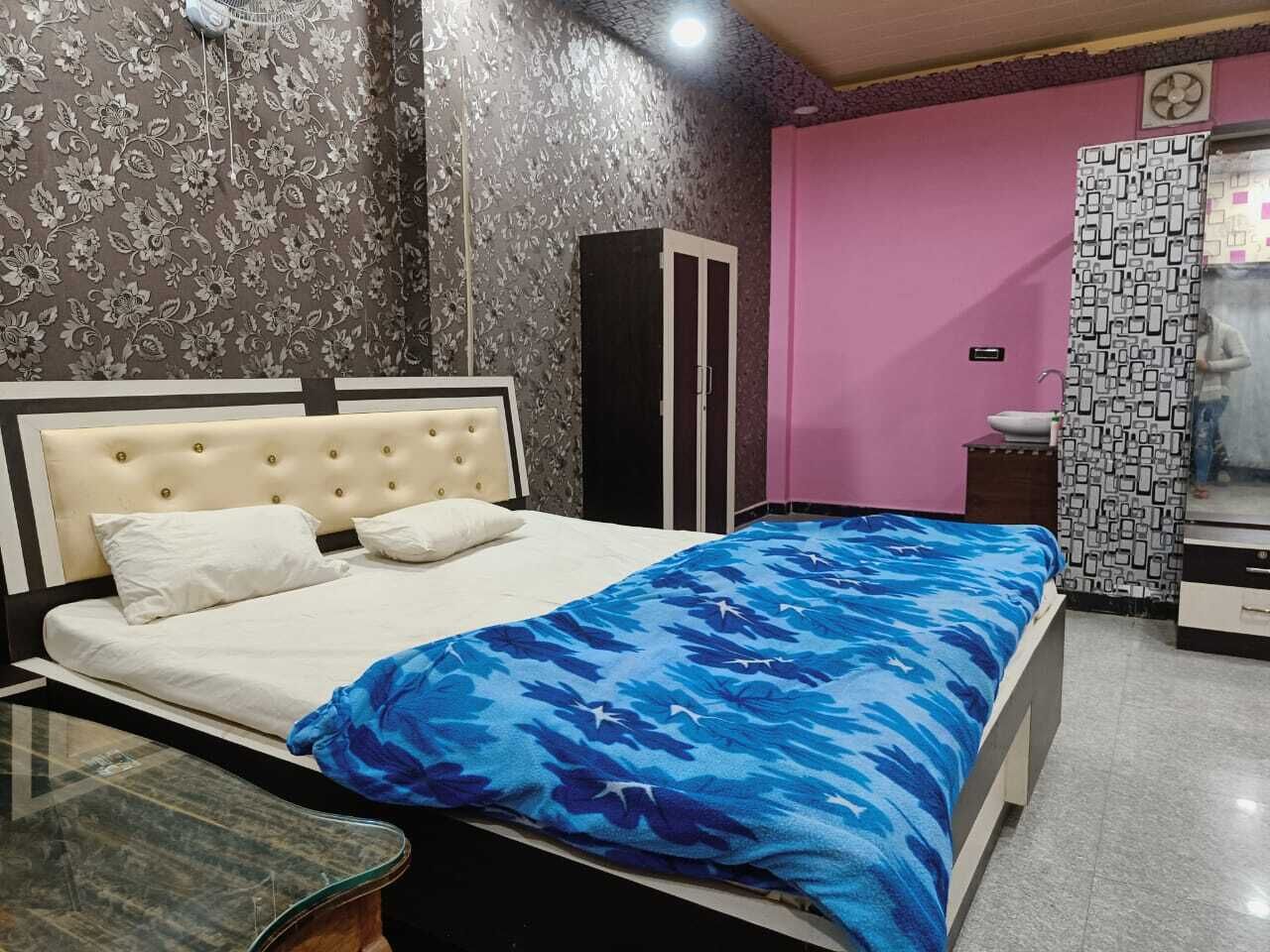 Un dormitorio con cama, armario, espejo y una mesita.