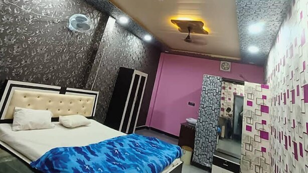 A bedroom with a bed, ceiling fans, and patterned walls. - Tridev Restaurant By GRB (Muzaffarpur)