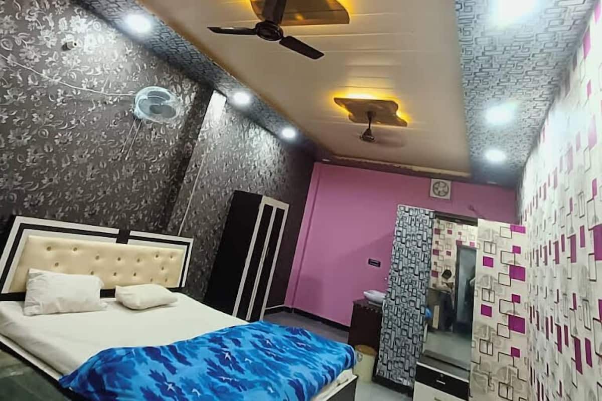 A bedroom with a bed, ceiling fans, and patterned walls.