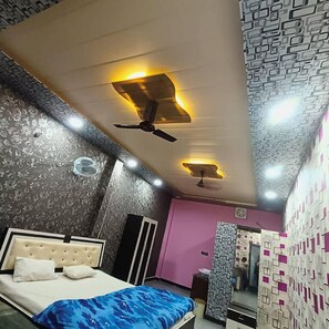 A bedroom with a bed, ceiling fans, and patterned walls. - Tridev Restaurant By GRB (Muzaffarpur)