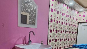 A bathroom with a pink wall, a sink, a mirror, and a patterned wall. - Tridev Restaurant By GRB (Muzaffarpur)