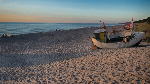 Una playa con un bote en la arena.