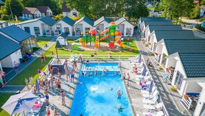 Zona de piscina con tobogán, sillas de descanso y una pequeña área de juegos.
