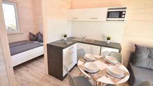 Una cocina compacta con comedor, una cama empotrada y un microondas.