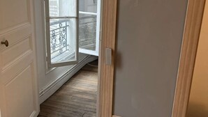A room with a wooden floor, a white door, and a view of a balcony with a railing. - Apartment near Montparnasse and Port Royal (Paris)