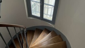 A wooden spiral staircase with a window above it. - Apartment near Montparnasse and Port Royal (Paris)
