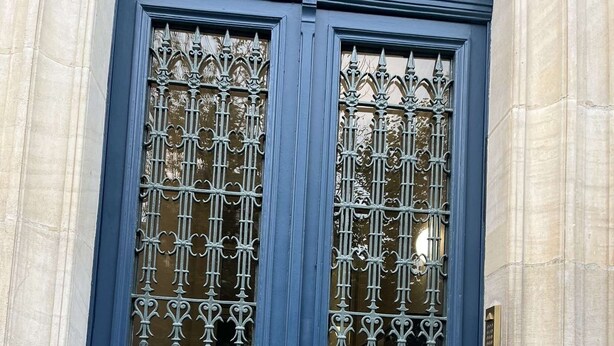 A dark blue double door with ornate metal grilles and a brass handle. - Apartment near Montparnasse and Port Royal (Paris)