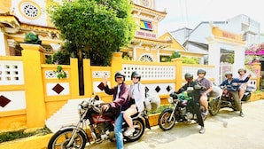 A group of people on motorcycles parked in front of a building with yellow walls and decorative elements. - Good Morning Hoi An Homestay and Hostel (Da Nang)