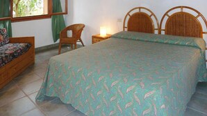 Ein Schlafzimmer mit Bett, Stuhl, Nachttisch und Fenster.