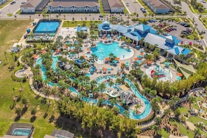 An aerial view of a resort with multiple swimming pools, water slides, and lounge areas surrounded by palm trees and buildings.