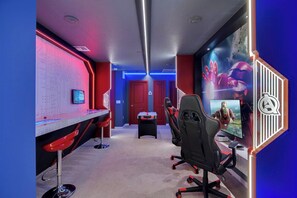 A gaming room with a desk, chairs, a computer, and a large poster. - 5BR townhouse w/ private pool & balcony (Davenport)