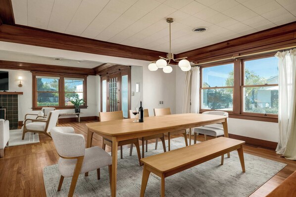 Un comedor con una mesa de madera, sillas, un banco y una araña.