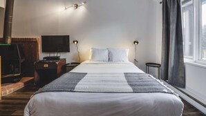Habitación de hotel moderna con una cama grande, un televisor de pantalla plana, dos lámparas de noche y vistas al exterior a través de una ventana.