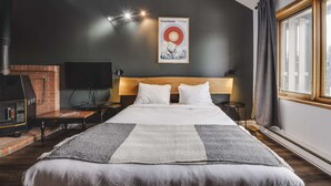 A hotel room with a bed, a fireplace, a television, and a poster on the wall. - Studio Courchevel 2 (Mezz 2 Q - 1 DL) - 6 people (Saint-Ferréol-les-Neiges)