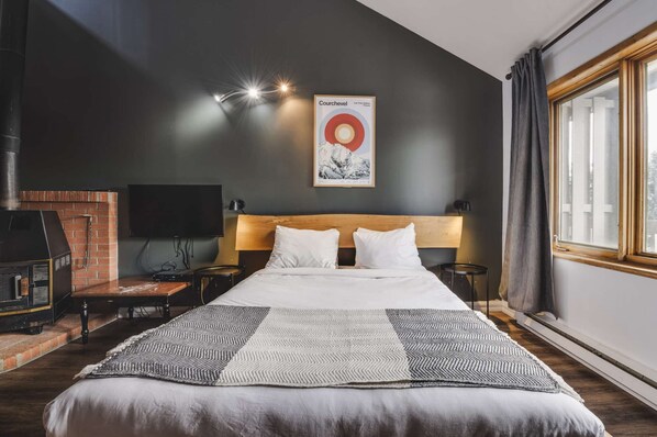 A hotel room with a bed, a fireplace, a television, and a poster on the wall.