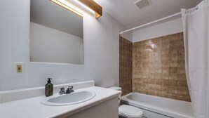 A bathroom with a white sink, a toilet, and a shower area with brown tiles. - Studio Courchevel 2 (Mezz 2 Q - 1 DL) - 6 people (Saint-Ferréol-les-Neiges)