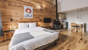 A spacious bedroom with a large bed, wooden walls, a mounted TV, and a fireplace. - Studio Courchevel 3 (Mezz 2 Q - 1 DL) - 6 people (Saint-Ferréol-les-Neiges)
