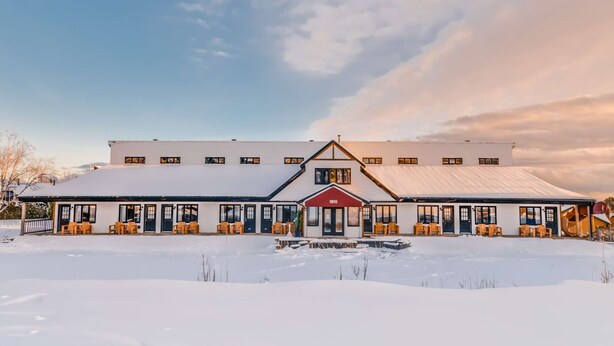 En stor, moderne bygning med en symmetrisk facade, flere indgange og en rød hoveddør i midten.