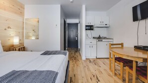 A hotel room with a bed, a desk, a chair, a kitchenette, and a TV. - Studio St-Anton 8 (1 Q) - 2 people (Saint-Ferréol-les-Neiges)