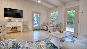 A cozy living room with a flat-screen TV, striped armchairs, a sofa, and a coffee table. - Experience coastal bliss at Sand Dollar Daze, a spacious 3-bedroom home in Oak Island. (Oak Island)