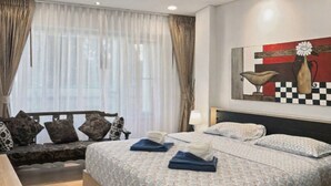 A hotel room with a large bed, a sofa, and a painting on the wall.