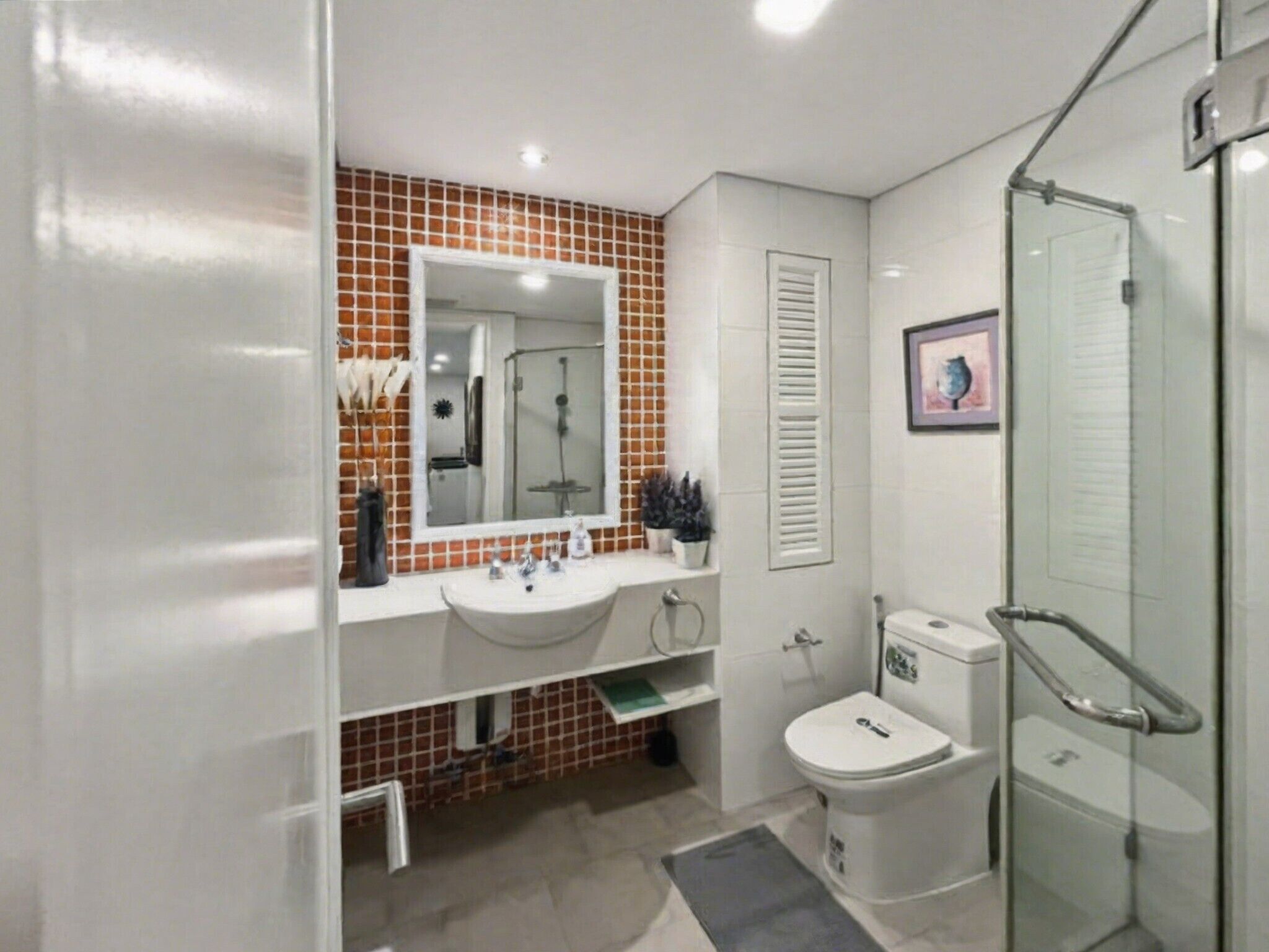 A bathroom with a white sink, a mirror, a shower, and a toilet.