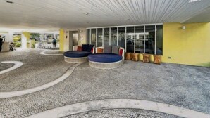 A modern lounge area with circular seating, a textured floor, and a ceiling with linear patterns.