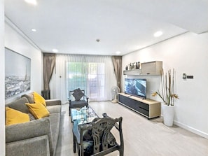 Ein modernes Wohnzimmer mit einer Couch, einem Couchtisch, einem Fernseher und dekorativen Pflanzen.