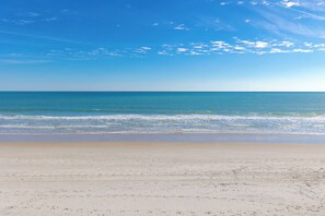 Uma praia com céu claro e mar calmo.