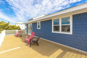 Um deck externo coberto com piso de madeira e duas cadeiras Adirondack.