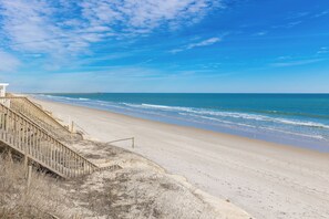A beach with a wooden staircase leading down to the shore, a pier in the distance, and clear blue skies. - Fancy Free - Oceanfront 4 BR. (Surf City)